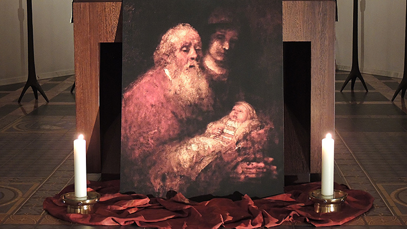 Eingerahmt von zwei brennenden Kerzen steht die Rembrandt Darstellung von Simeon und Hanna vor dem Altar.